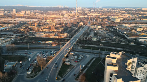 Video - Aerial drone view of Chisiniau at sunset. Multiple buildings, roads with multiple cars, thermal station's tubes, bridge over the railroad. Bare trees, winter