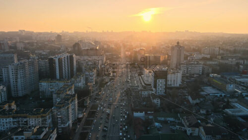 Video - CHISINAU, MOLDOVA - JANUARY 17, 2021: Aerial drone view of city at sunset. Multiple residential and commercial buildings, roads with multiple cars. Bare trees, winter