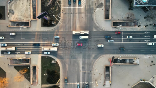 Video - Aerial drone view of intersection at sunset. Road with multiple cars, walking people, underground passage. Bare trees, winter