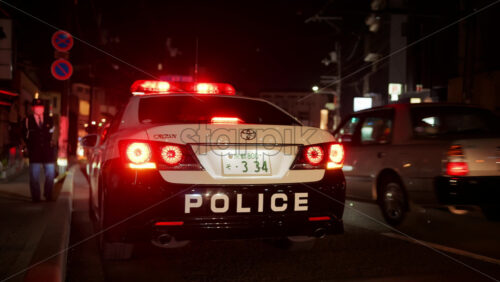 Video - Kyoto, Japan - April 11, 2025: Police car with red lights on the street in the Gion area in the evening