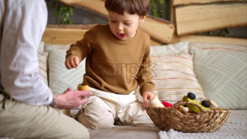 Video - Father playing with his son with colourful, ecological wooden toys on the bed