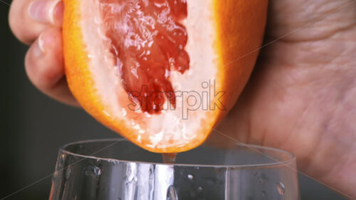 Video - A woman squeezes juice from the grapefruit into a glass. Slow motion