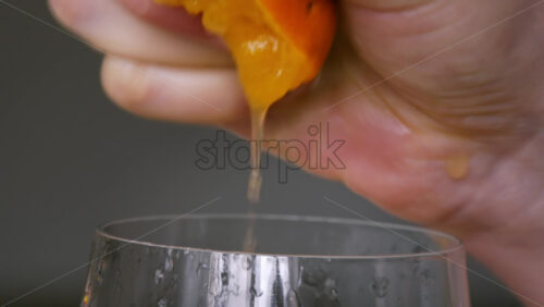 Video - A woman squeezes juice from an orange into a glass. Slow motion