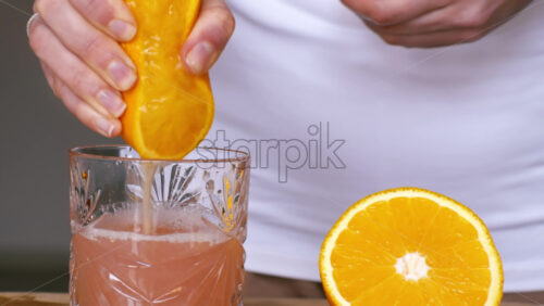 Video - A woman squeezes juice from a lime into a glass. Slow motion