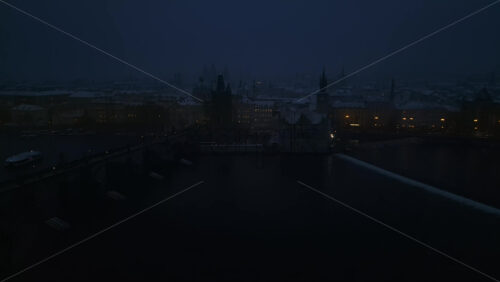 Video - Aerial drone view of Powder Tower and the medieval Charles bridge covered in snow in the night. Winter in Prague, Czech Republic