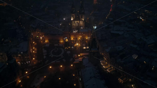Video - Aerial drone view of the ancient gothic Church of Our Lady before Tyn in the Old Town square covered in snow at night. Winter in Prague, Czech Republic