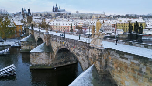 Video - Aerial drone of the medieval stone Charles bridge covered in snow in the daylight. Winter in Prague, Czech Republic