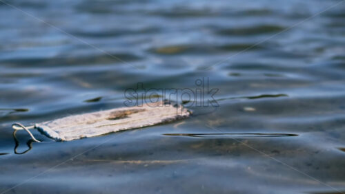 Video - Dirty medical mask floating floating on water. Pollution idea