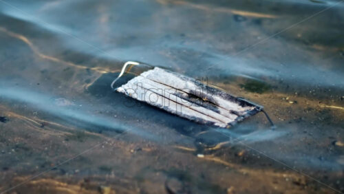 Video - Dirty medical mask floating floating on water. Pollution idea