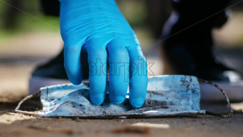 Video - Man in medical gloves picking up dirty medical mask from the ground from the ground. Pollution idea