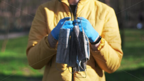 Video - Man in medical gloves holding a bunch of dirty medical masks raised from the ground. Pollution idea