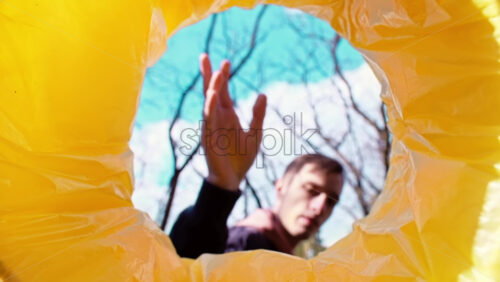 Video - Man throwing a green plastic bottle into a trash can. View from inside the can. Slow motion