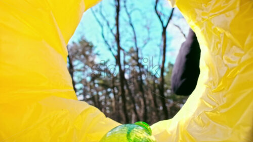 Video - Man throwing a green plastic bottle into a trash can. View from inside the can. Slow motion