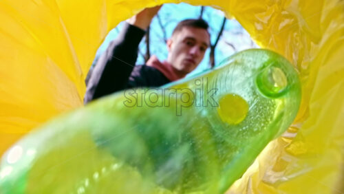 Video - Man throwing a green plastic bottle into a trash can. View from inside the can. Slow motion