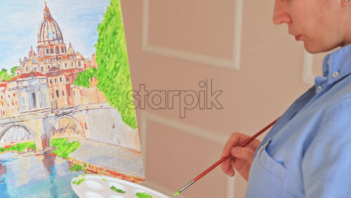 Video - Woman painting picture on the easel holding a palette at home