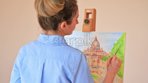 Video - Woman painting picture on the easel holding a palette at home