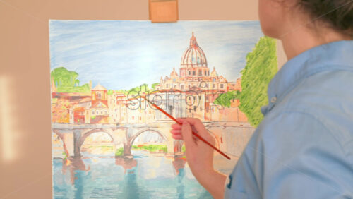 Video - Caucasian woman painting a picture with a palette in her hands and listening music with earphones indoors