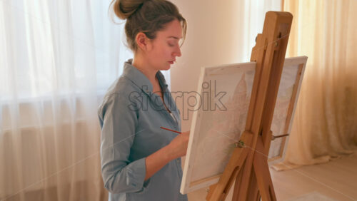 Video - Caucasian woman painting a picture with a palette in her hands, indoors