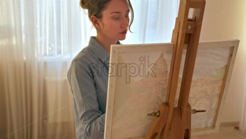 Video - Caucasian woman painting a picture with a palette in her hands, indoors