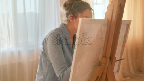 Video - Caucasian woman painting a picture with a palette in her hands, indoors. Slow motion