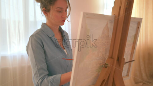 Video - Caucasian woman painting a picture with a palette in her hands, indoors. Slow motion
