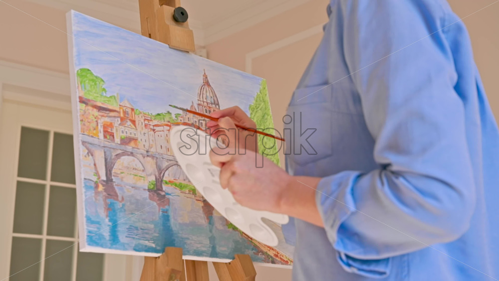 Video - Caucasian woman painting a picture with a palette in her hands, indoors. Slow motion