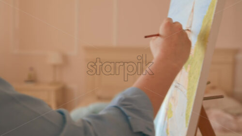 Video - Caucasian woman painting a picture with a palette in her hands, indoors