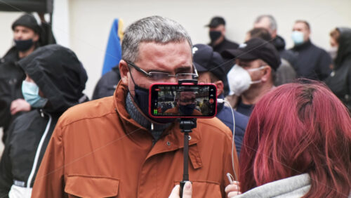 Video - CHISINAU, MOLDOVA - APRIL 28, 2021: Woman filming a talking man on smartphone. People protesting for snap elections in front of constitutional court building