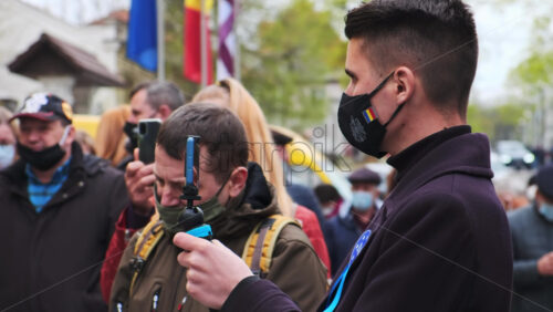 Video - CHISINAU, MOLDOVA - APRIL 28, 2021: Young man shooting a group of talking people on smartphone. People protesting for snap elections in front of constitutional court building