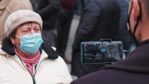 Video - CHISINAU, MOLDOVA - APRIL 28, 2021: Man filming a talking woman on smartphone. People protesting for snap elections in front of constitutional court building