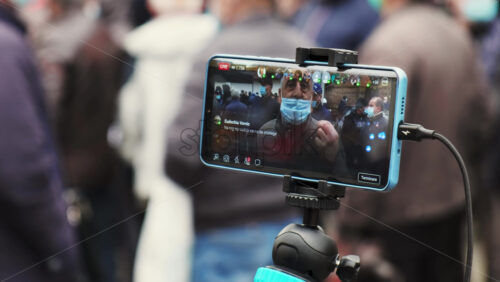 Video - CHISINAU, MOLDOVA - APRIL 28, 2021: Shooting of a talking man on smartphone. People protesting for snap elections in front of constitutional court building