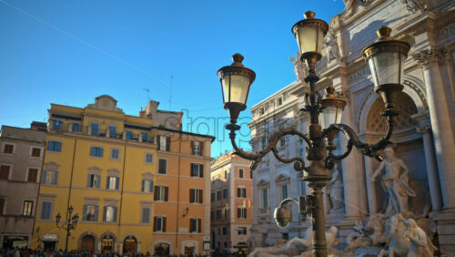 Video - Rome, Italy - February 13, 2024: Street lamp with the Trevi Fountain in background at sunset