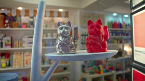 Video - Silver and red lucky cats sitting on a shelf in a store