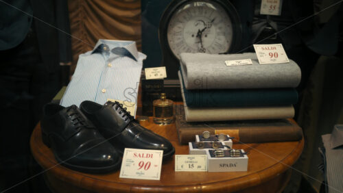 Video - Rome, Italy - February 14, 2024: Wooden table with clothes, a pair of black shoes and accessories in a clothing store