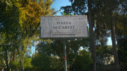 Video - Marble sign of Bucharest square surrounded by trees in sunlight. Rome, Italy
