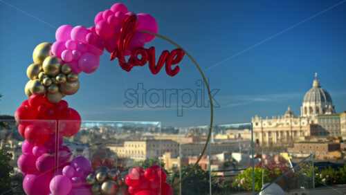 Video - Pink, red and gold, love balloon arch at panoramic view of Vatican City, Rome, Italy.