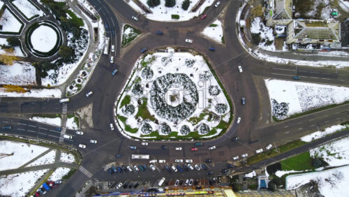 Video - Aerial drone view of a roundabout intersection. Roads with moving cars, bare trees, snow on the ground. Chisinau, Moldova