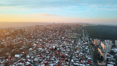 Video - Aerial drone view of Chisinau at sunrise. Panorama view of a residential district with multiple buildings, roads and bare trees. Good weather, snow on the ground. Moldova