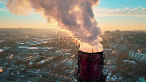 Video - Aerial drone view of Chisinau at sunrise. Thermal station with smoke coming out of the tube. Buildings, roads and bare trees on the background. Good weather, snow on the ground. Moldova
