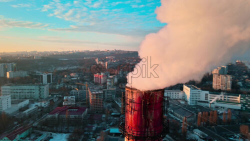 Video - Aerial drone view of Chisinau at sunrise. Thermal station with smoke coming out of the tube. Buildings, roads and bare trees on the background. Good weather, snow on the ground. Moldova