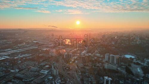 Video - Aerial drone view of Chisinau at sunrise. Panorama view of multiple buildings, roads with moving cars and bare trees. Good weather with snow on the ground. Moldova