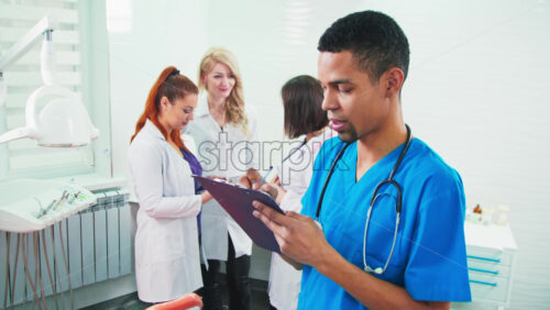 Video - Doctors in the dental office. Three talking nurses and one noting doctor