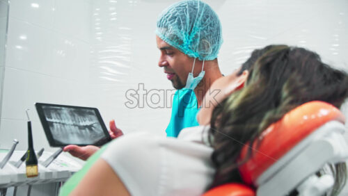 Video - Doctor in the dental office with patient at the examination, doctor showing the roentgen image on a tablet