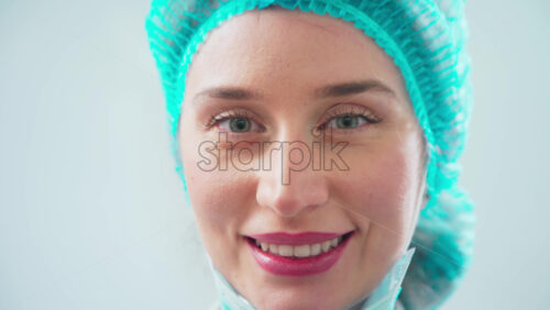 Video - Doctor in medical hat taking off mask and smiling in the dental office looking into the camera