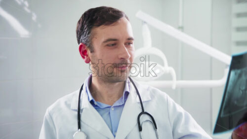 Video - Doctor in the dental office looking at the roentgen image and into the camera