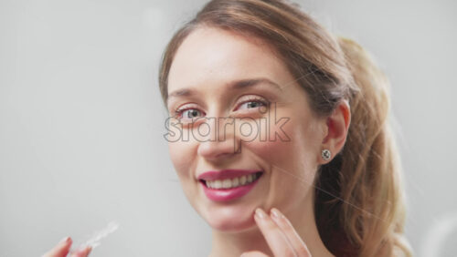 Video - Portrait of a woman looking into the camera and taking off dental cap