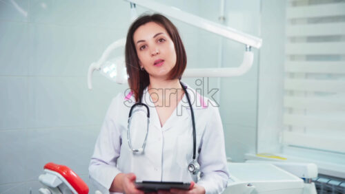 Video - Doctor in the dental office looking into the camera and using tablet