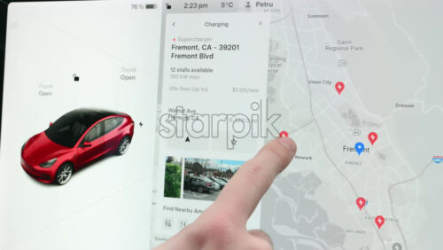 Video - Chisinau, Moldova - January 23, 2024: Male hands choosing the pins on the map, representing the closest charging location in the area. Touch screen of the red Tesla Model 3 electric car