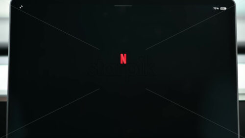 Video - Chisinau, Moldova - January 23, 2024: Male hand opening Netflix application on the red Tesla Model 3 electric car. Light theme