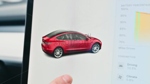 Video - Chisinau, Moldova - January 23, 2024: Male hands rotating the 3D model of red Tesla Model 3 electric car in the status area of the touch screen. Light theme
